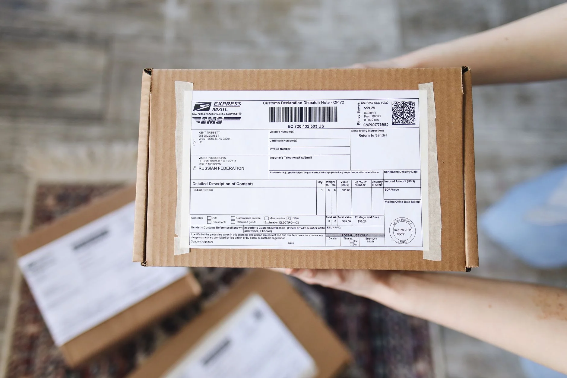 Persona aplicando una etiqueta impresa sobre la caja de un producto en una mesa de trabajo