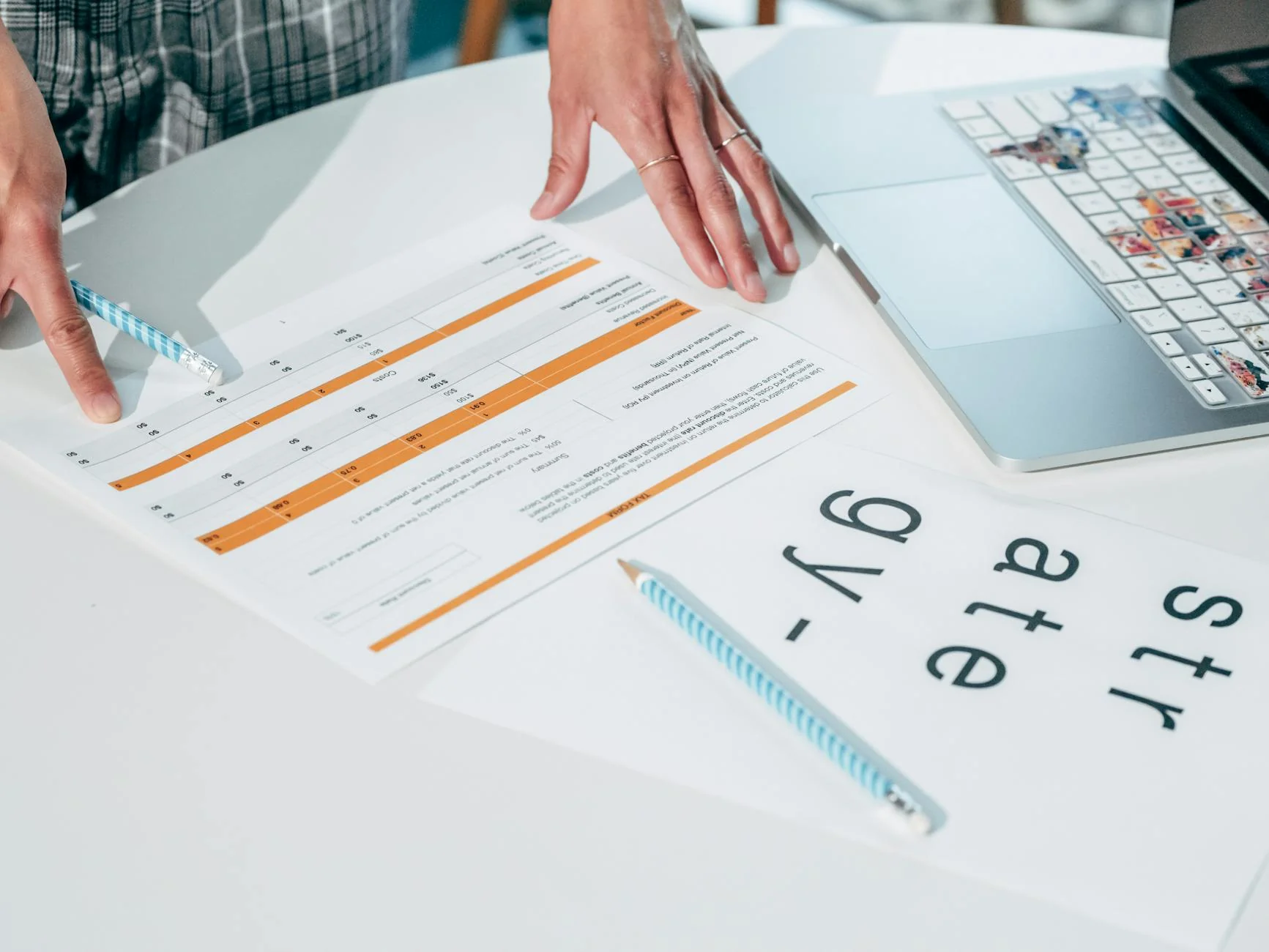 A person at a desk reviewing a printed product document next to a laptop and a packaged consumer good