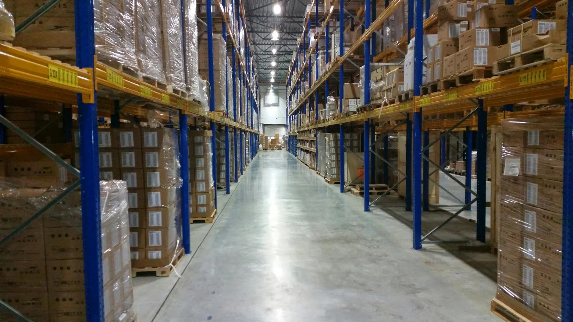 Rows of cardboard shipping boxes stacked on metal shelving inside a large fulfilment warehouse