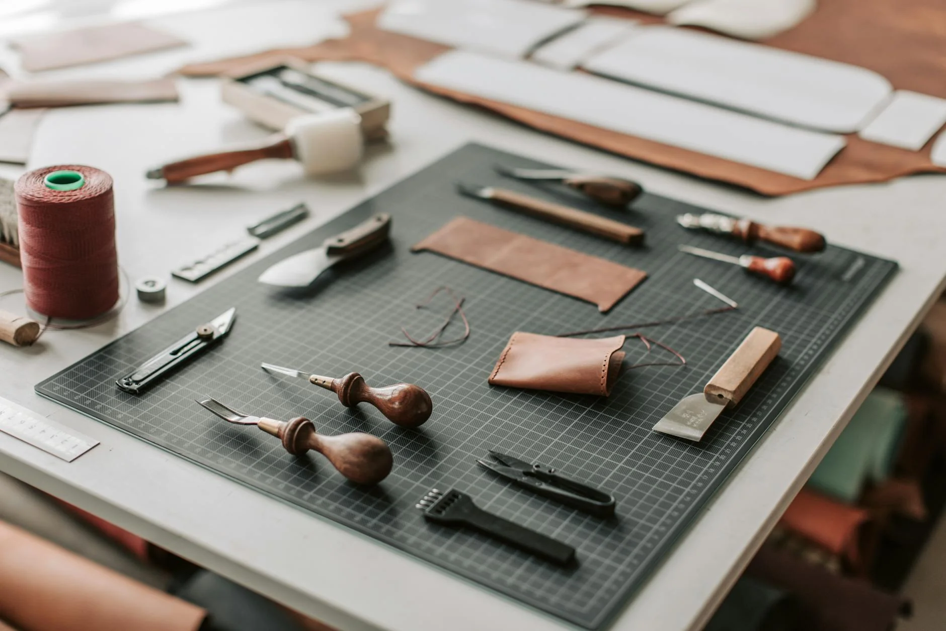 Handmade leather goods and tools laid out on a wooden craft workbench