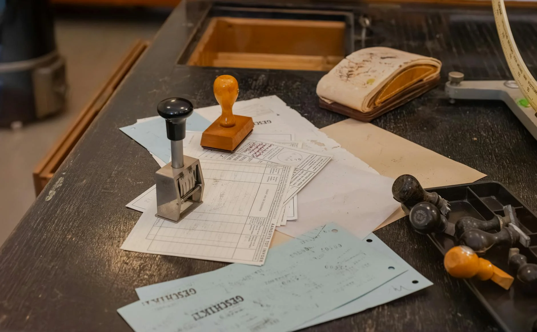 A wooden rubber stamp and ink pad resting on a stack of printed paper documents on a desk