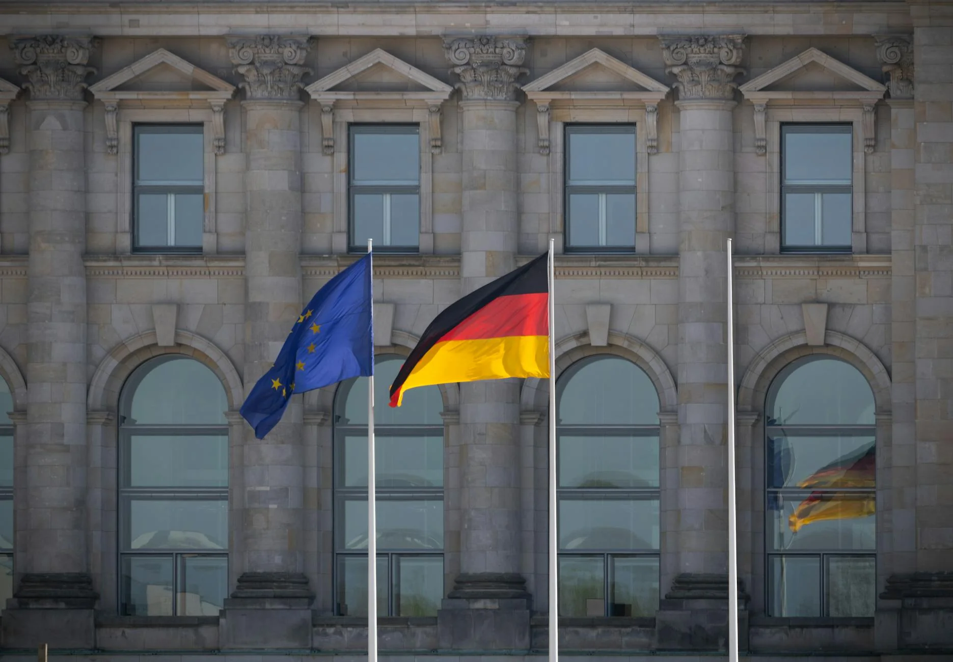 A row of national flags on poles outside an official building