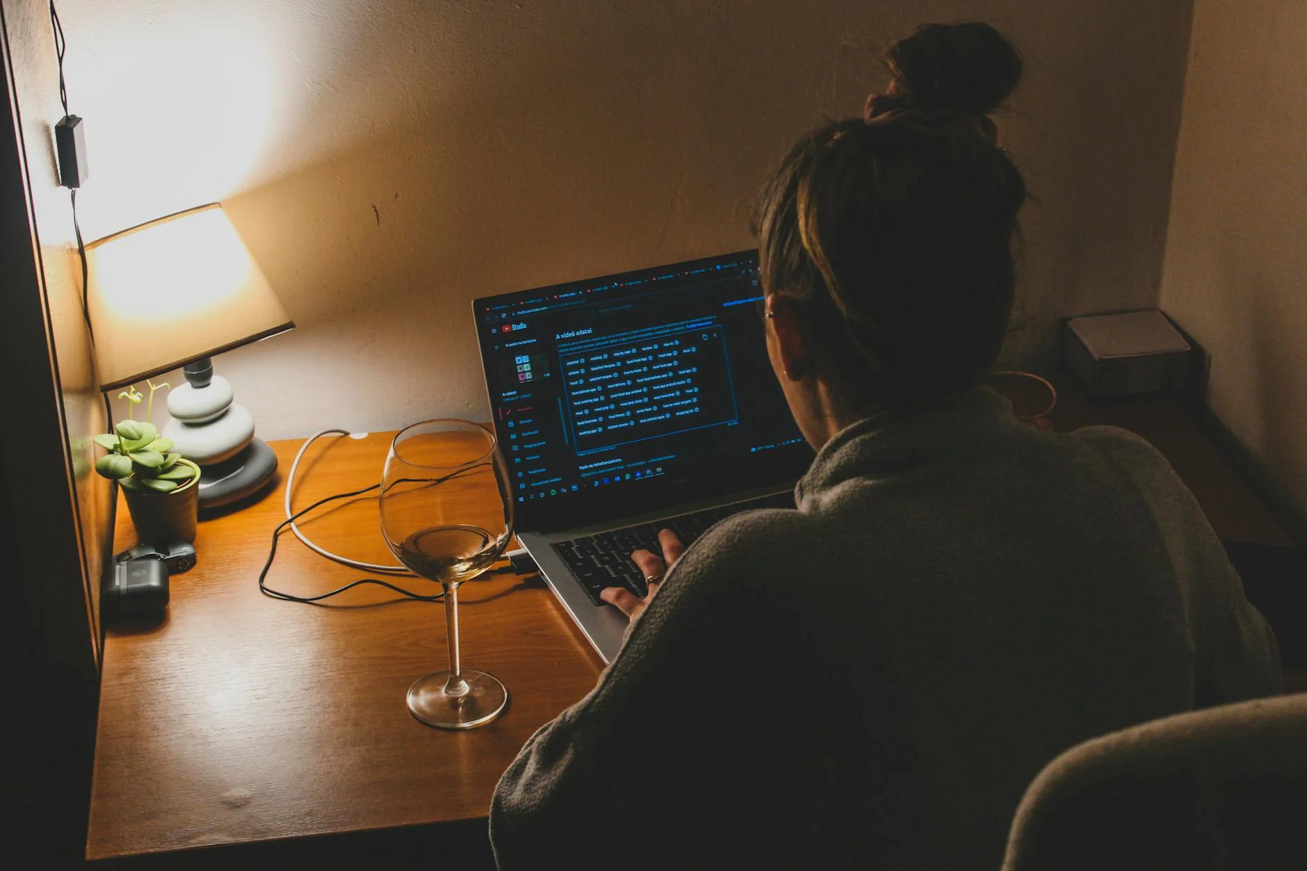 A person working at a desk with a laptop and a small smart home device beside it