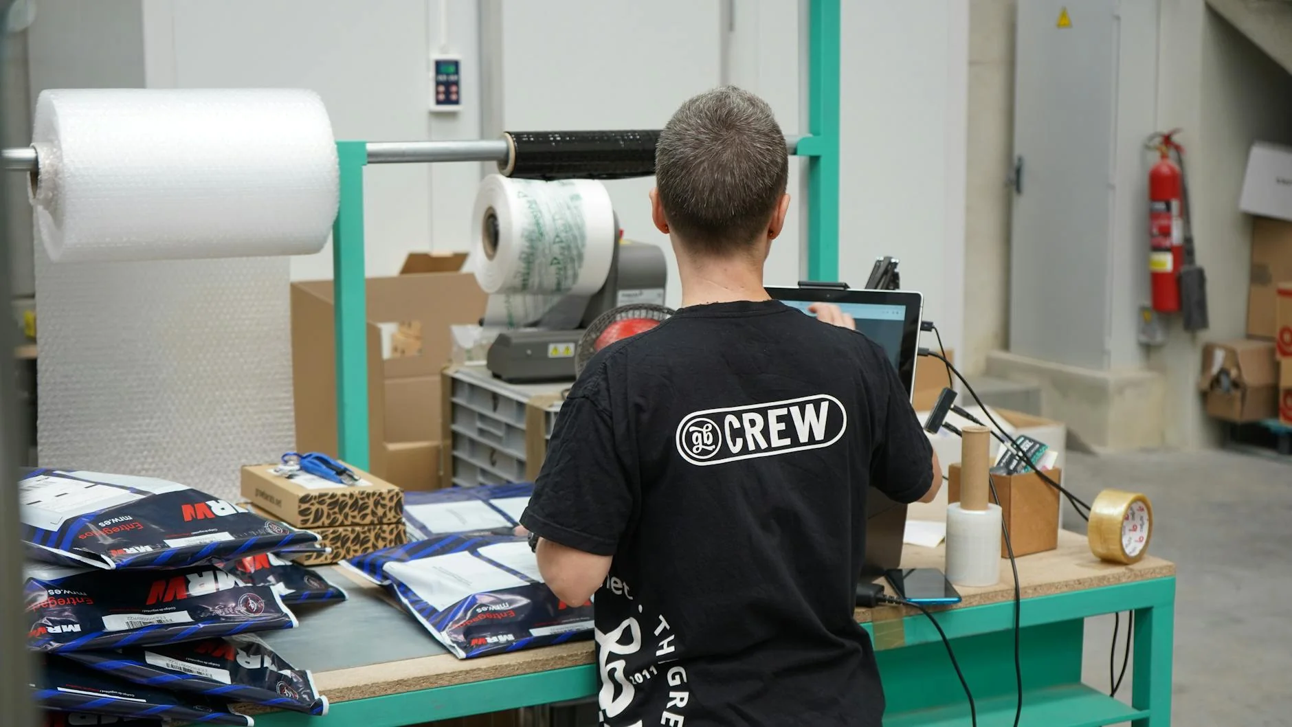 Tavolo di un magazzino con scatole di prodotti, etichette e documenti cartacei in revisione