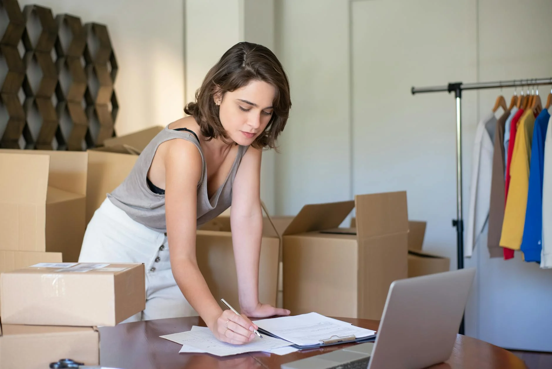 A seller reviews product paperwork at a desk with shipping boxes nearby.