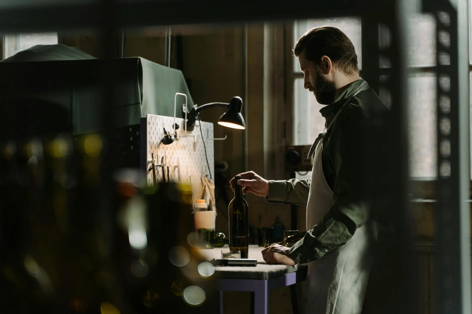 A maker inspects a handmade product against a checklist at a workbench.