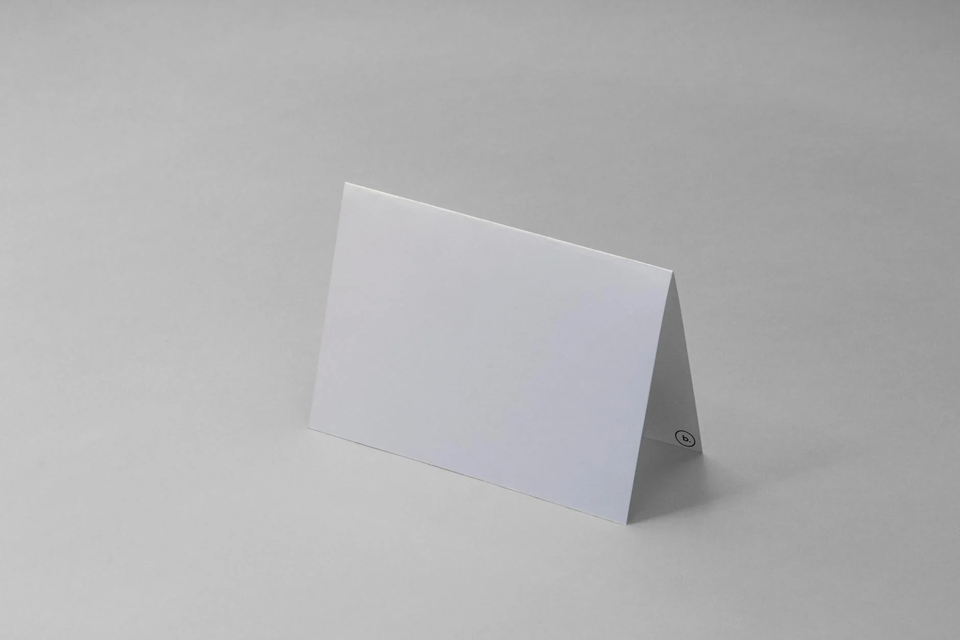 A pair of folded cotton socks and a stack of plain greeting cards on a wooden desk next to a laptop
