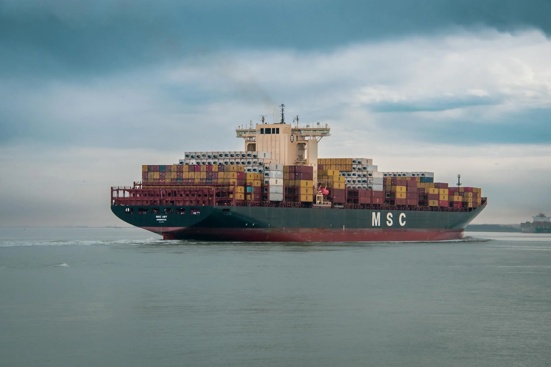 A cargo ferry loaded with shipping containers crossing the Irish Sea under an overcast sky