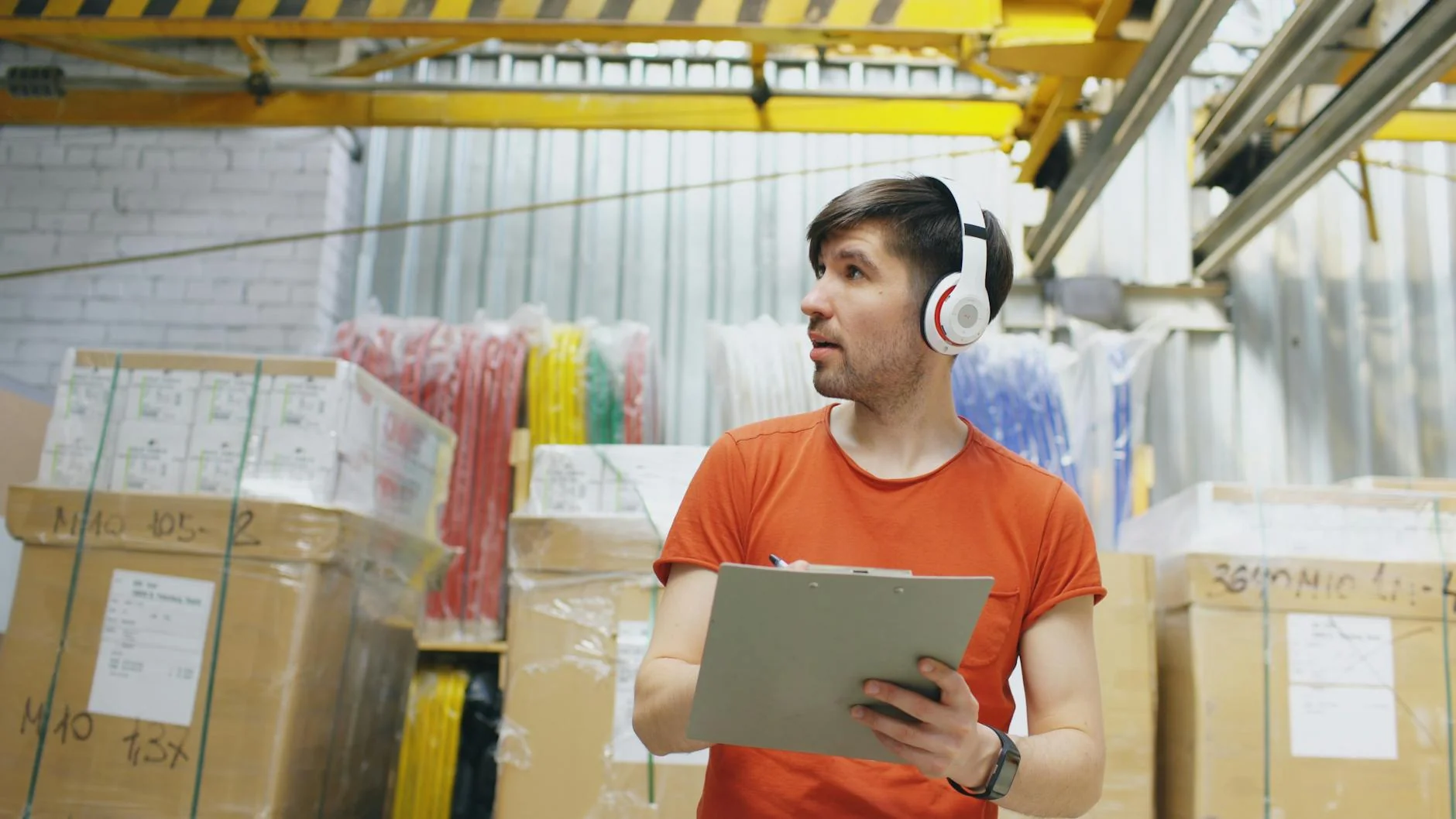Warehouse worker checking a cardboard parcel against a clipboard before shipping