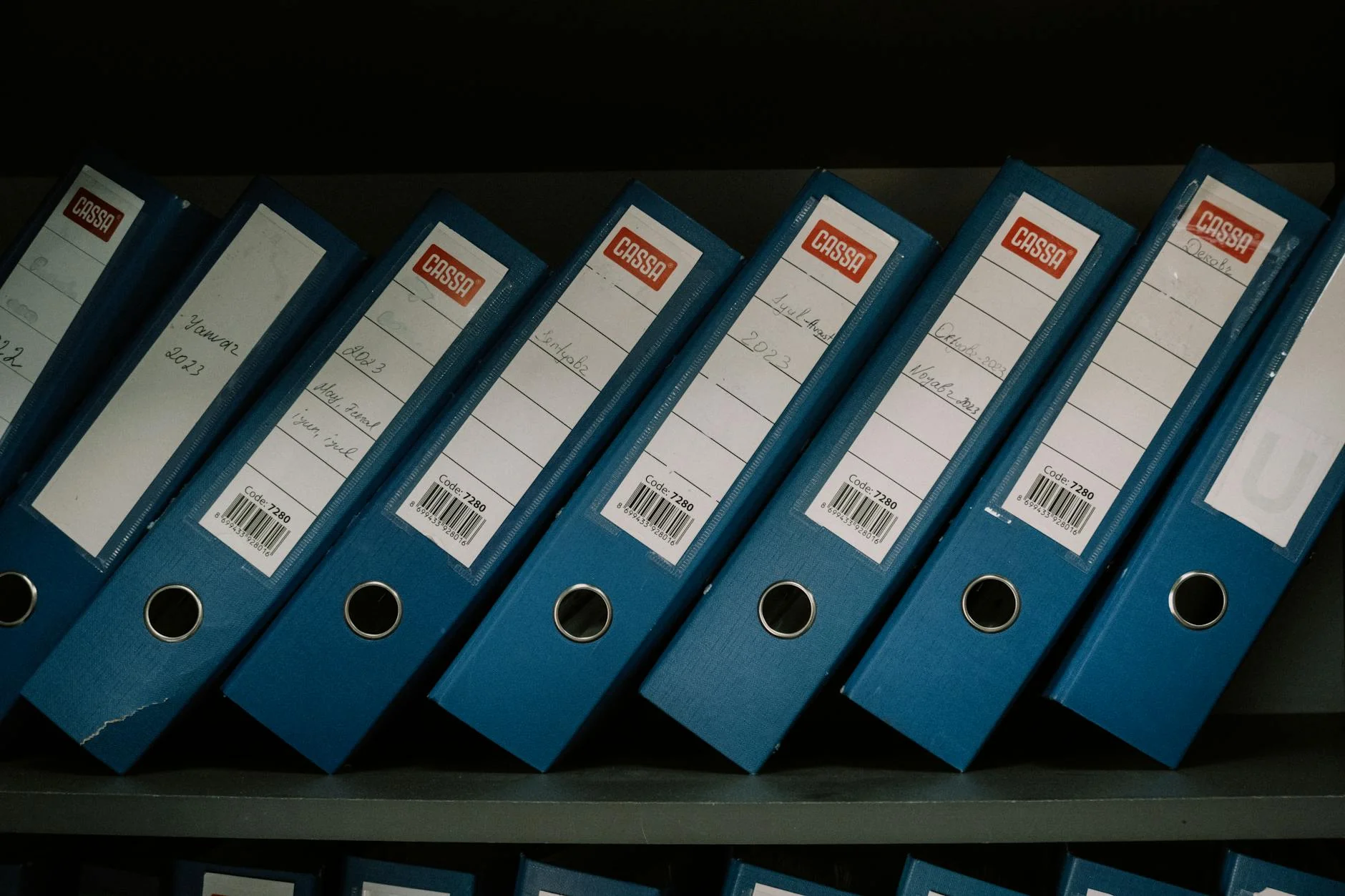 Rows of labeled archive boxes and binders stacked on metal shelving in a storage room